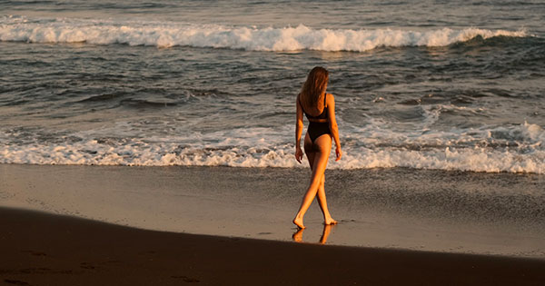 giovane donna passeggia in riva al mare tramonto