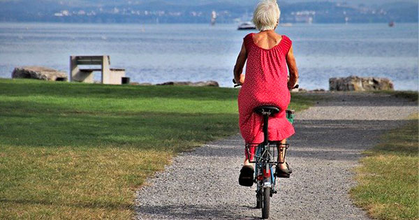 signora anziana bicicletta sentiero mare
