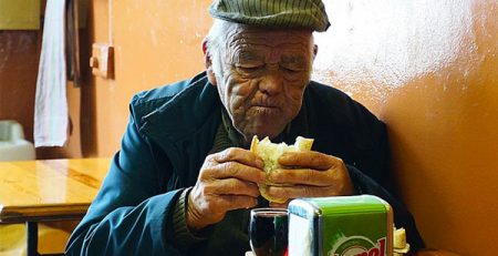 signore anziano mangia panino